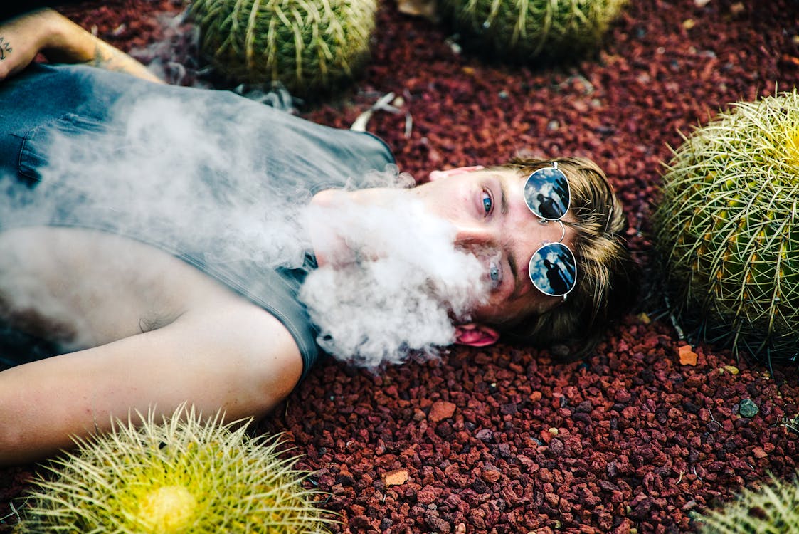 Free Person Smoking While Lying on Gravel With Cactus Stock Photo