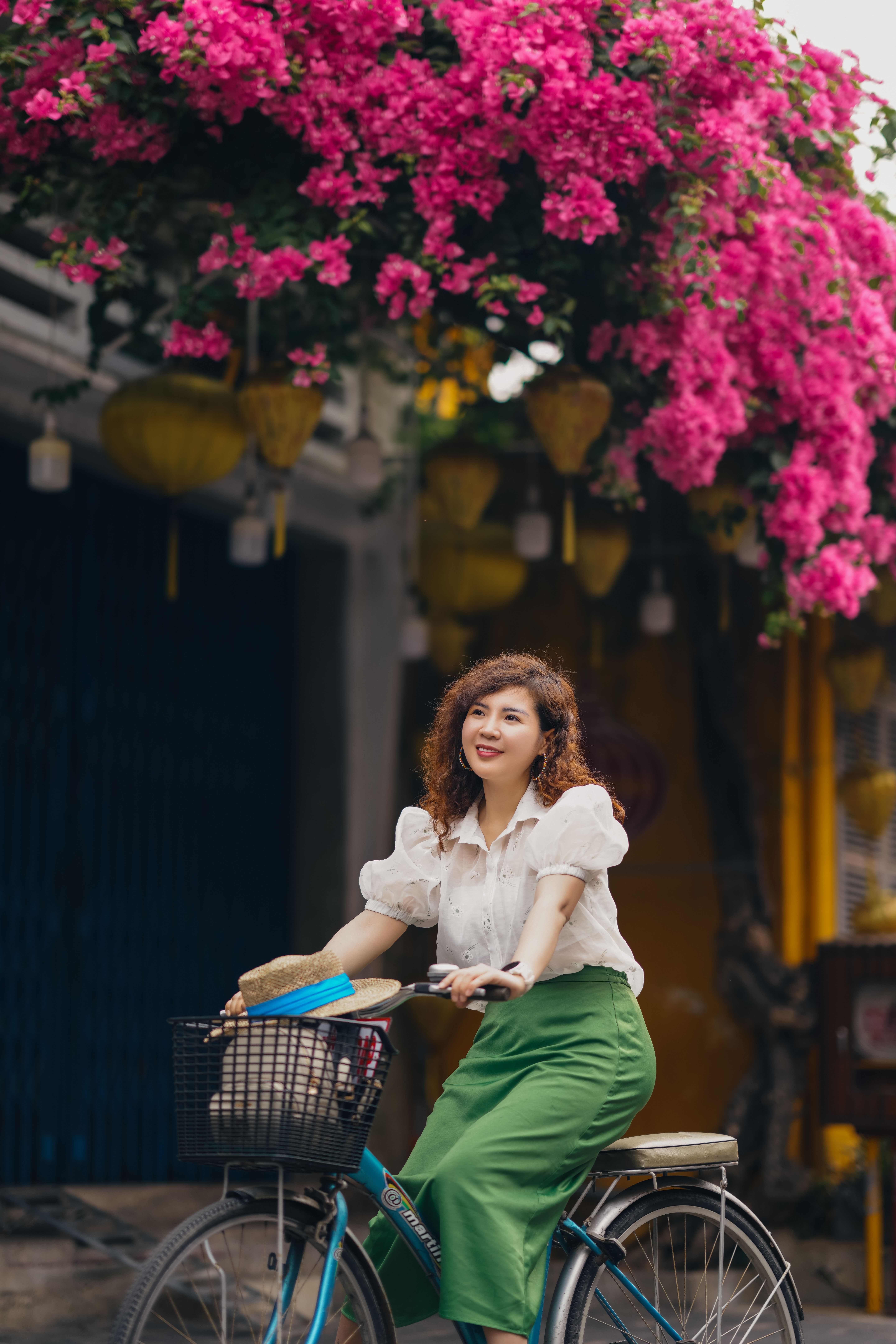 [ColoSach]-elegant-woman-with-a-bicycle-under-pink-bougainvillea-blooms-on-a-vibrant-city-street.