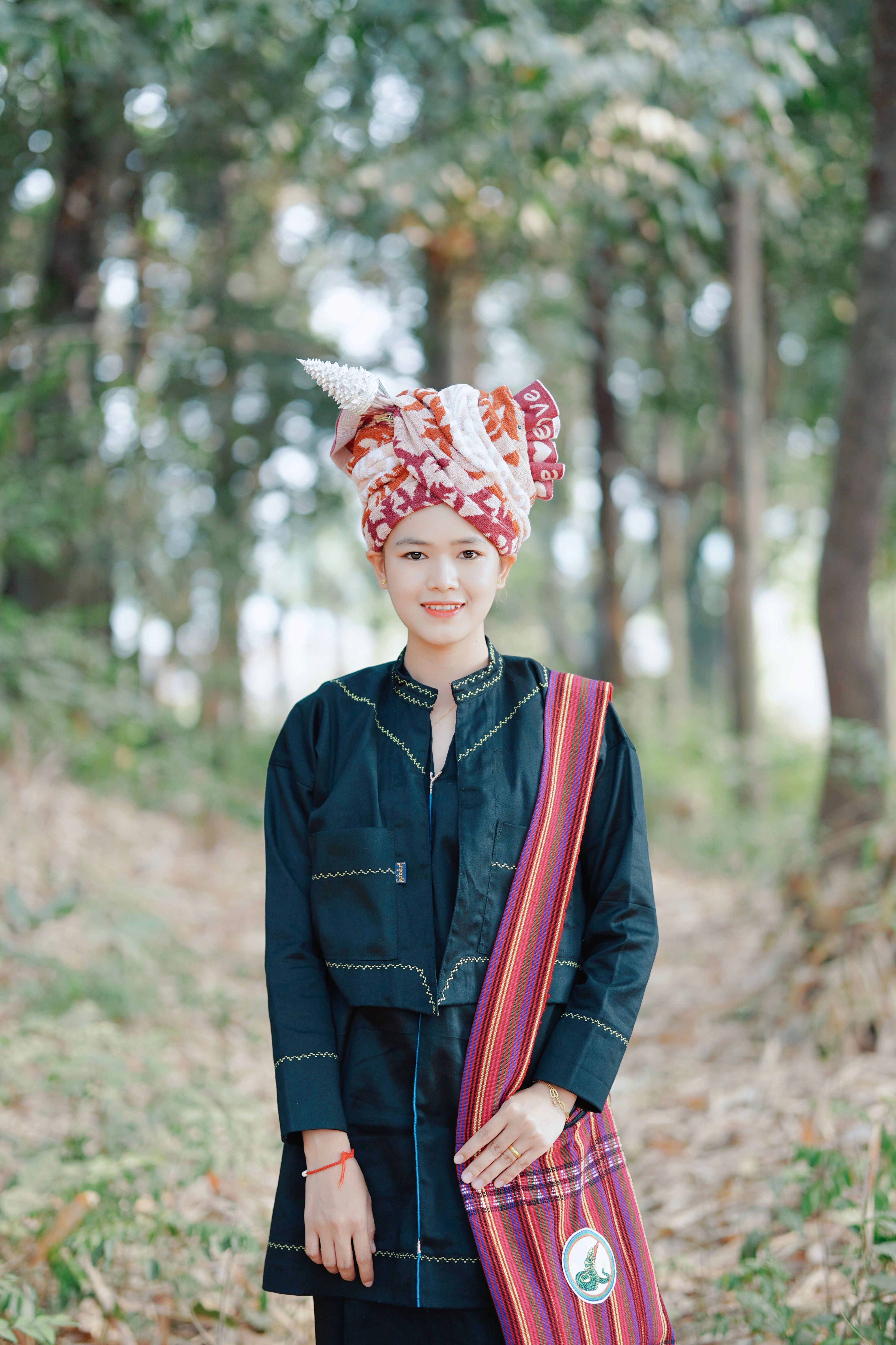 Portrait of a woman wearing traditional attire in a lush forest, showcasing cultural fashion.