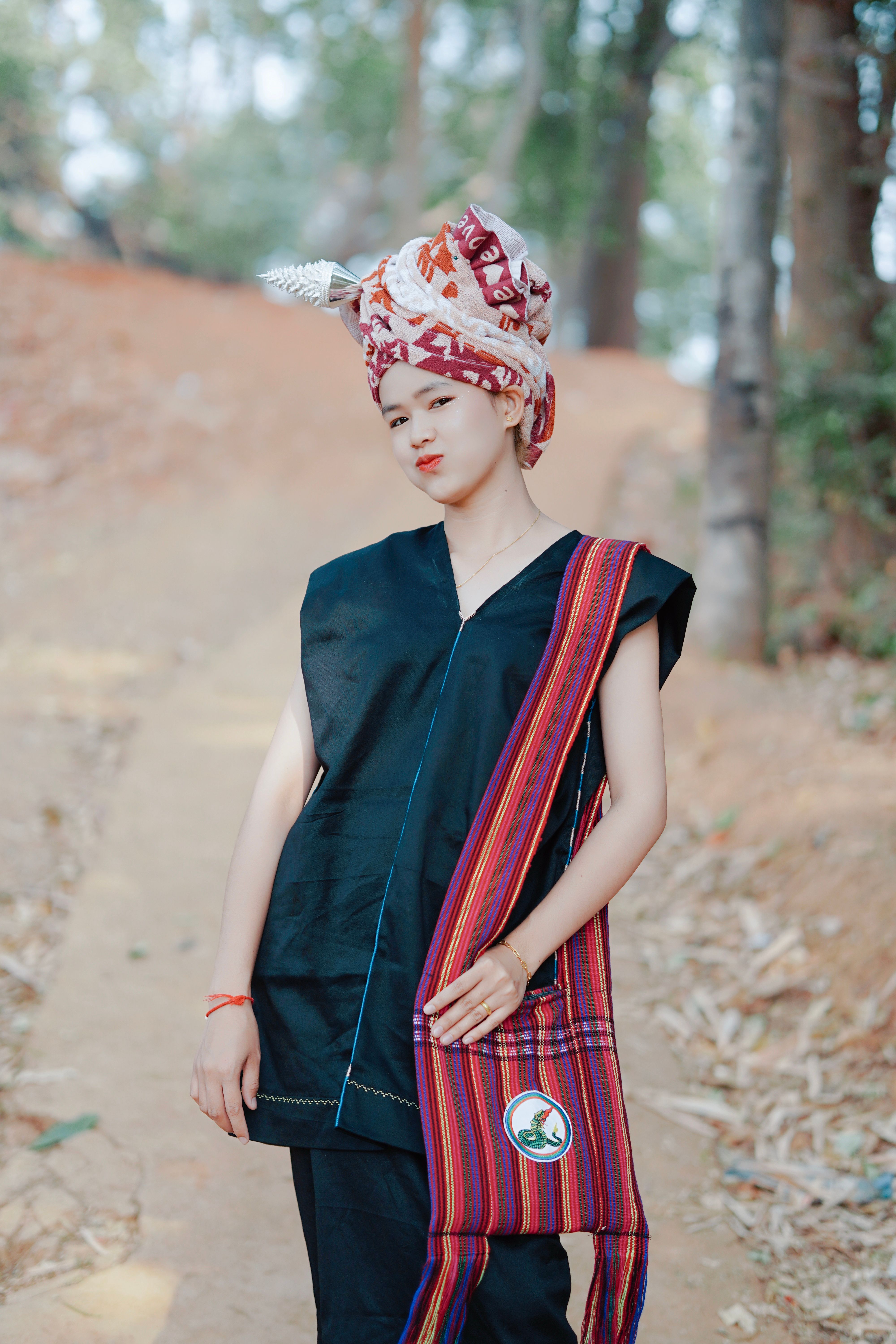 Young woman in traditional costume posing confidently outdoors in a forest setting.