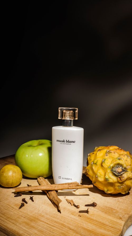 Free Still life of a perfume bottle with tropical fruits and spices on a wooden surface. Stock Photo