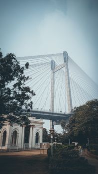 A serene view of the Howrah Bridge and Victoria Memorial in Kolkata, India, surrounded by lush greenery.