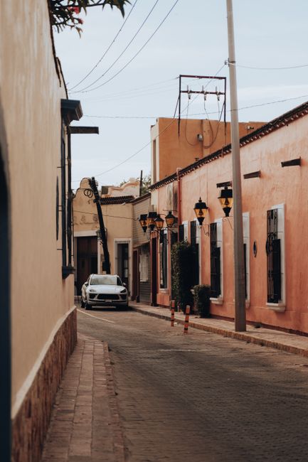 Colorful street in Tequisquiapan, Mexico with traditional architecture and a parked car.