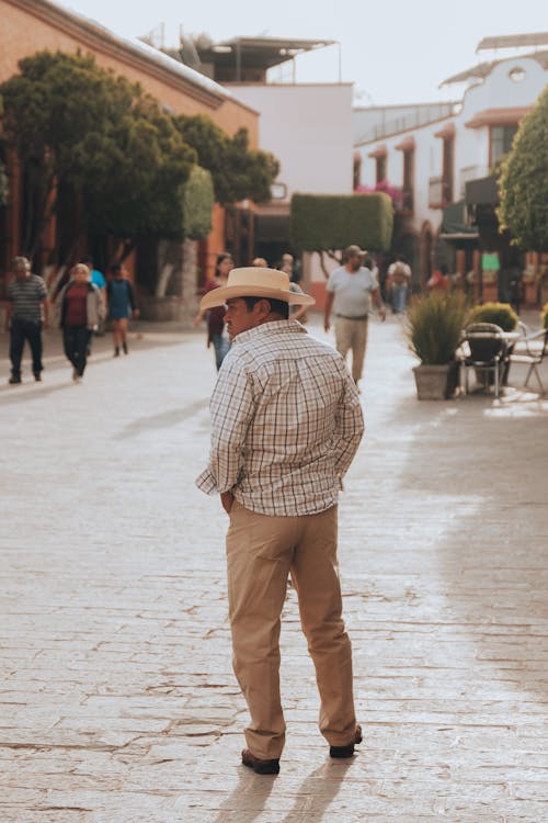 Man in Hat and Shirt on Street in Town