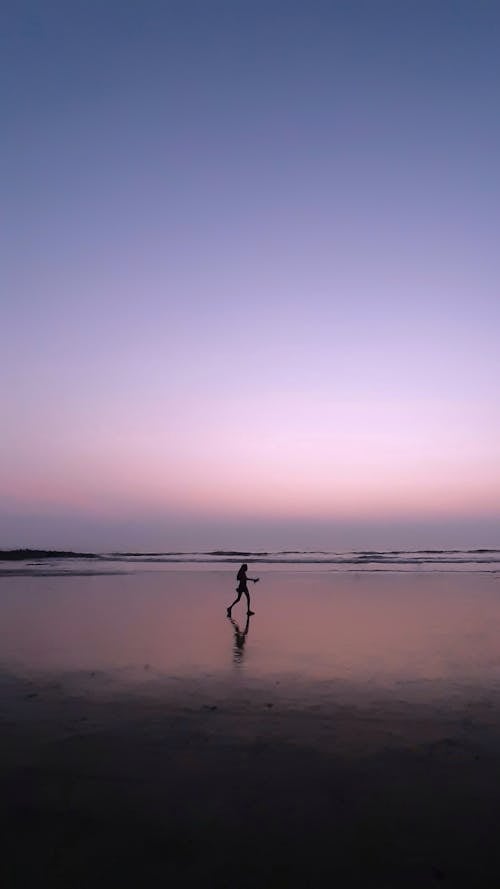 Woman Walking on Sea Shore at Dusk