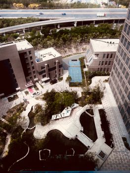 Aerial view of a modern urban complex with lush landscaping and nearby expressway.