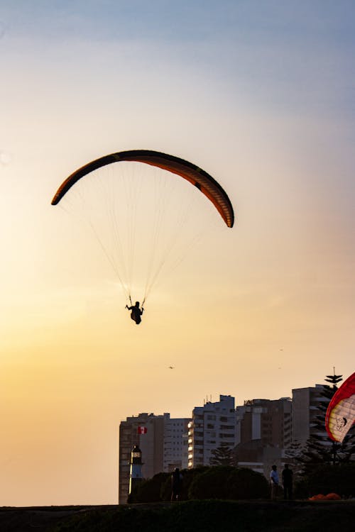 Person Parachuting over Town at Sunset
