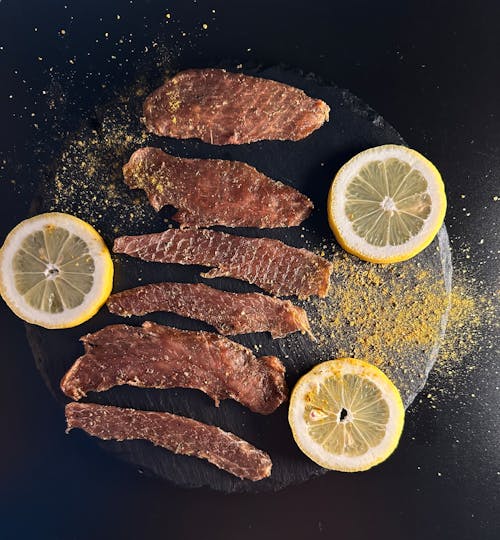 Strips of Meat Sprinkled with Turmeric Powder and Served with Slices of Lemon