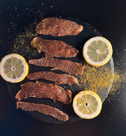 Free Top view of seasoned beef strips and fresh lemon slices on a slate surface. Stock Photo