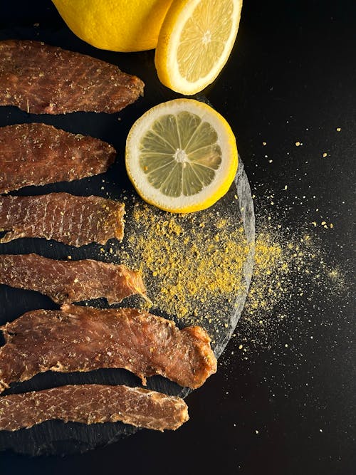 Strips of Meat Sprinkled with Turmeric Powder and Served with Lemon