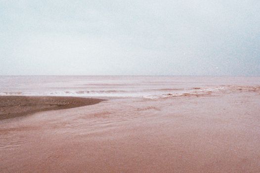 A calming view of an overcast beach with gentle waves, capturing the peaceful essence of the seashore.