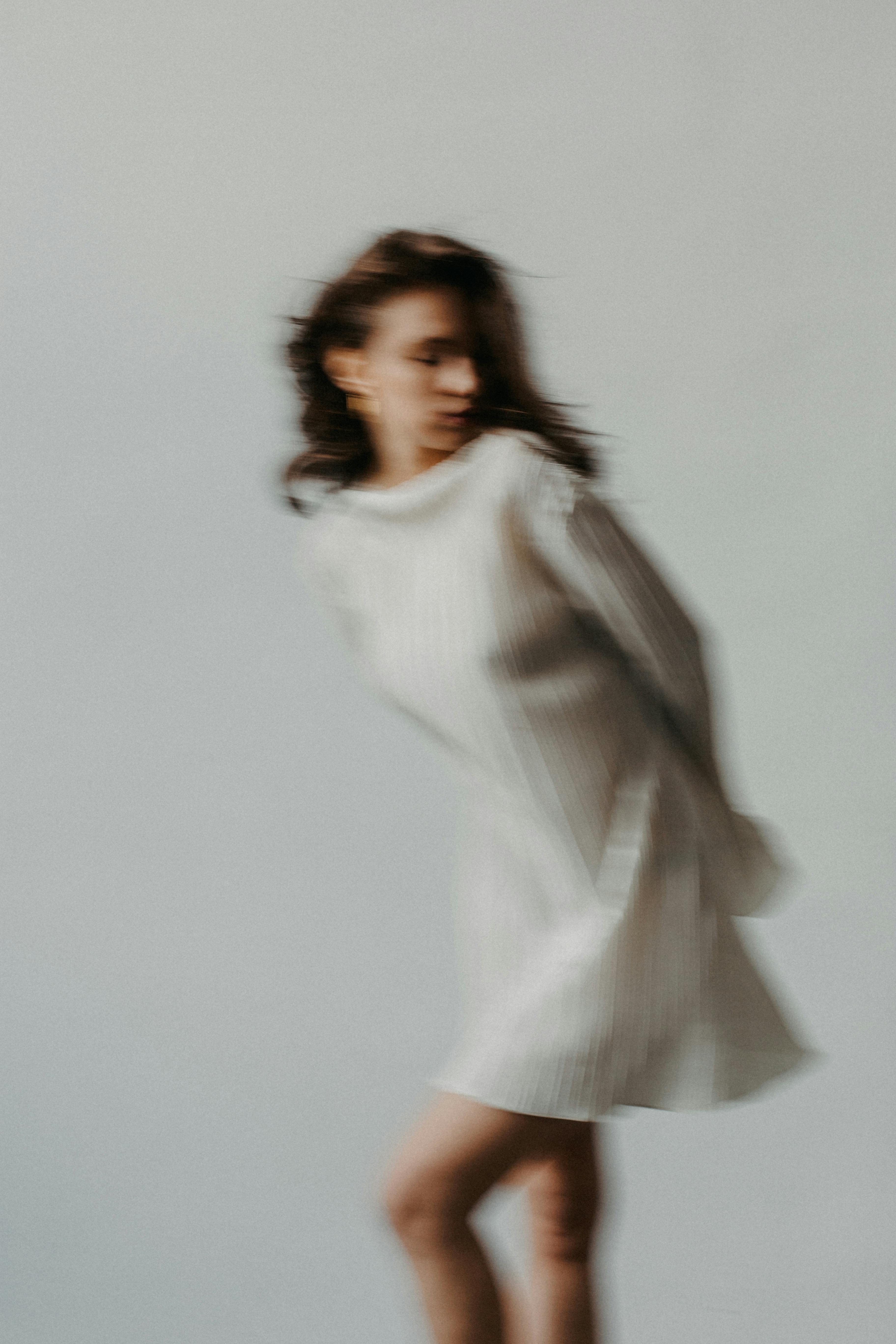 Fashion photography with blurred effect, capturing movement in a portrait of a woman in white.