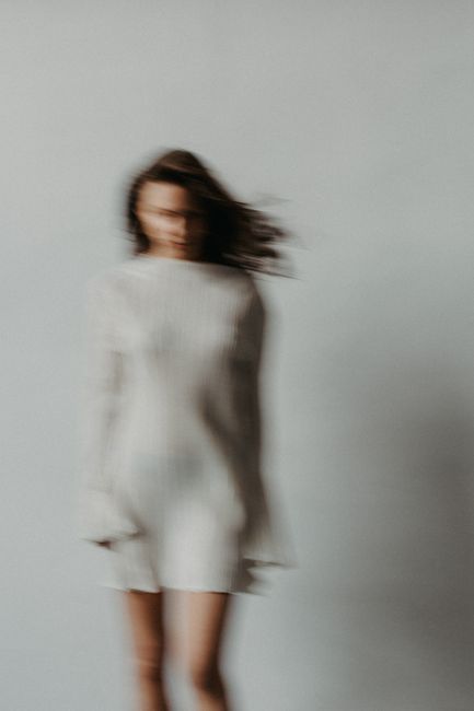Artistic blurred portrait of a woman in motion with long hair on a white background.