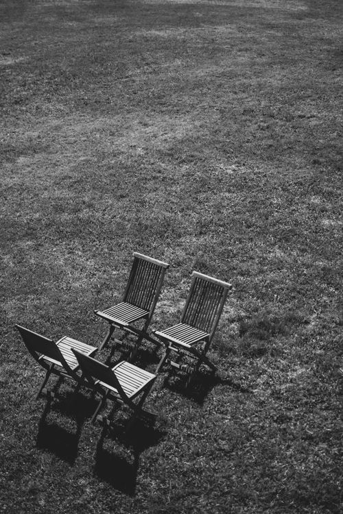 Free Aerial black and white image of four chairs arranged on grass, providing a minimalist and artistic perspective. Stock Photo