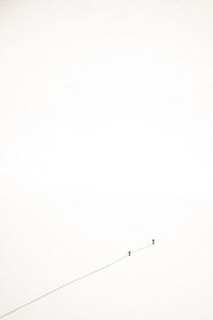 Two tiny silhouettes walking across a vast white, minimalist expanse.