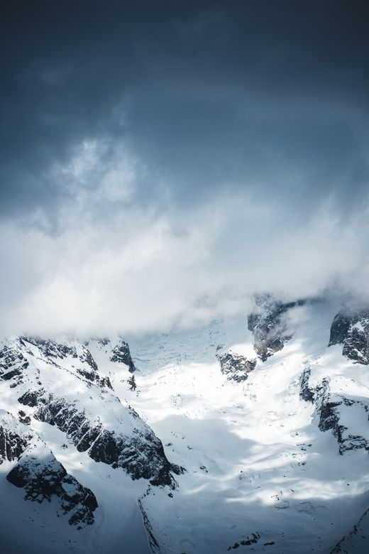 Snow-covered peaks breaking through low cloud — photo by Willian Justen de Vasconcellos on Pexels