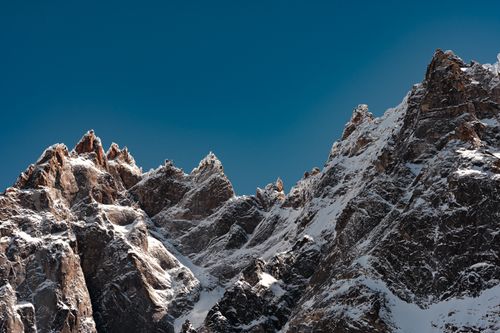 Free Majestic snow-capped mountain peaks with rugged landscapes under a clear blue sky. Stock Photo