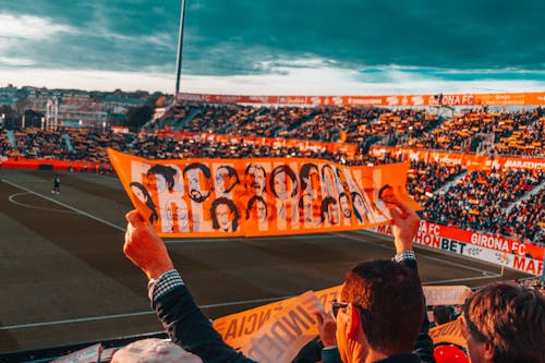 Person, Die Orange Banner Auf Stadion Hält