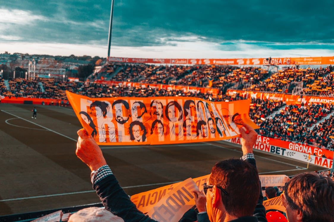 Free Person Holding Orange Banner on Stadium Stock Photo