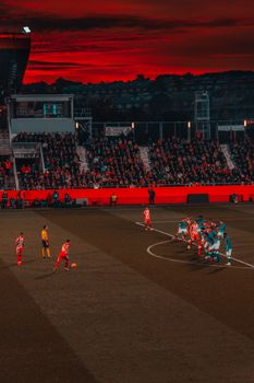 Exciting soccer match with teams in vibrant uniforms competing at sunset.