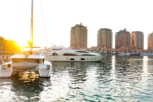 Scenic view of yachts docked at Doha marina with striking skyscrapers at sunset.
