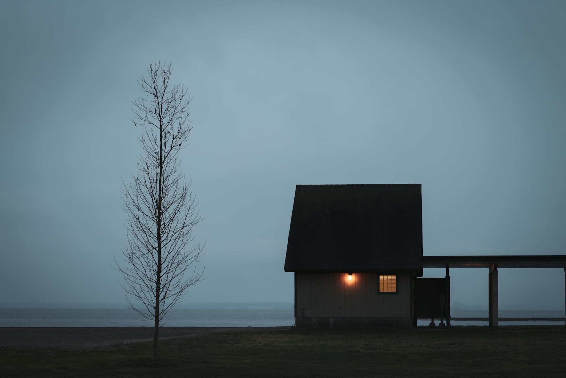 Silhouette of Cabin with Light in Fog