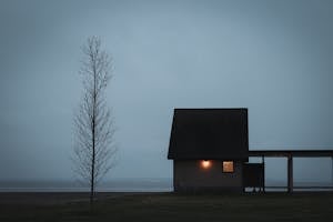 Silhouette of Cabin with Light in Fog
