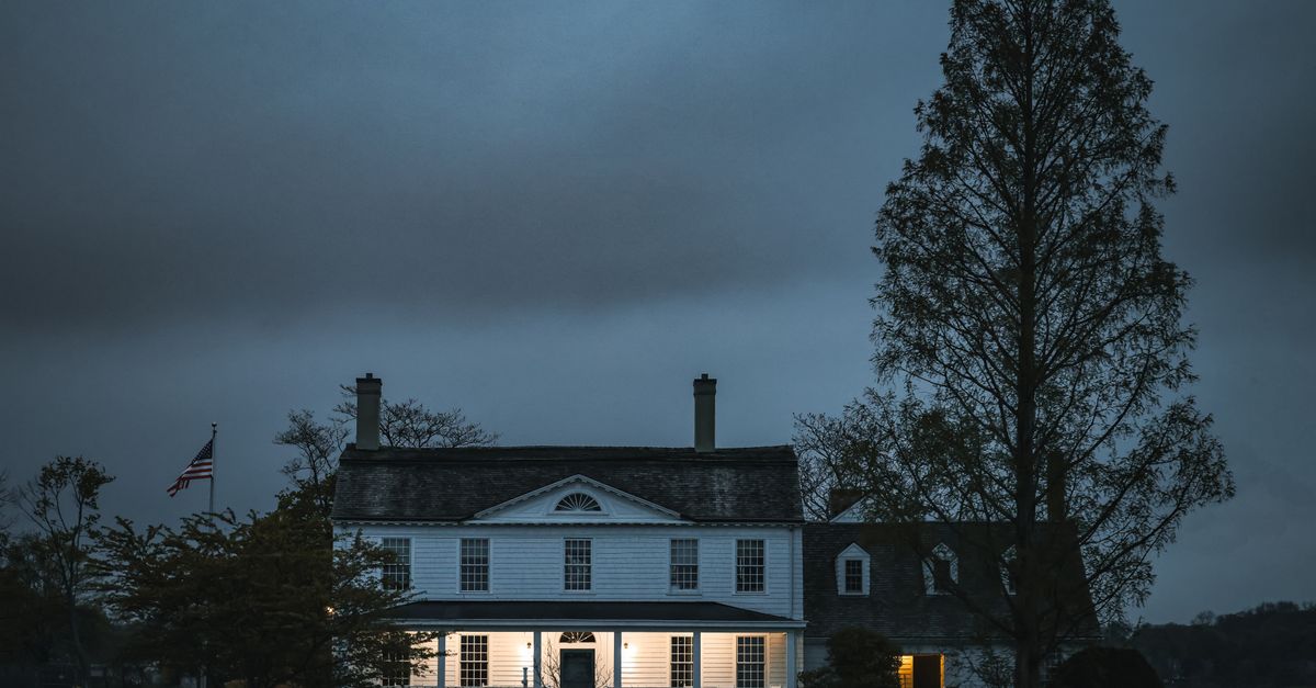 A picturesque colonial house illuminated during an overcast evening. Tranquil and inviting.