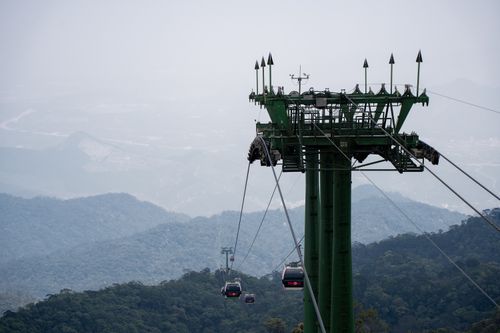 Free Aerial view of cable cars traveling over lush green hills, offering a serene landscape view. Stock Photo