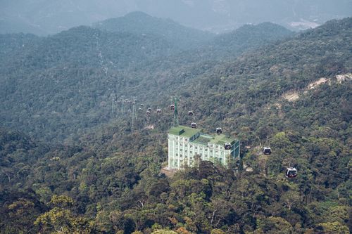 Free Aerial view of cable cars traversing a lush mountain forest with a scenic resort building. Stock Photo