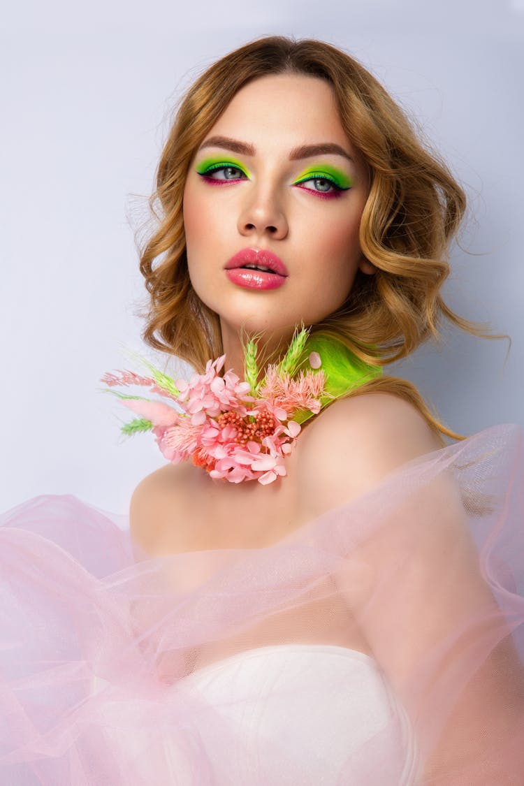 A Woman With Green Makeup And Pink Flowers