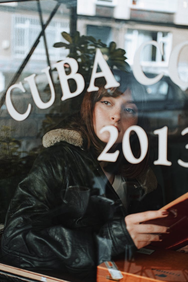 Woman Sitting In At A Restaurant Table And Looking Through Window