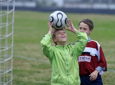 Two young boys enjoying a soccer practice on a grassy field.