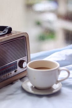 A cozy scene with a vintage radio and cup of coffee by a rainy window.