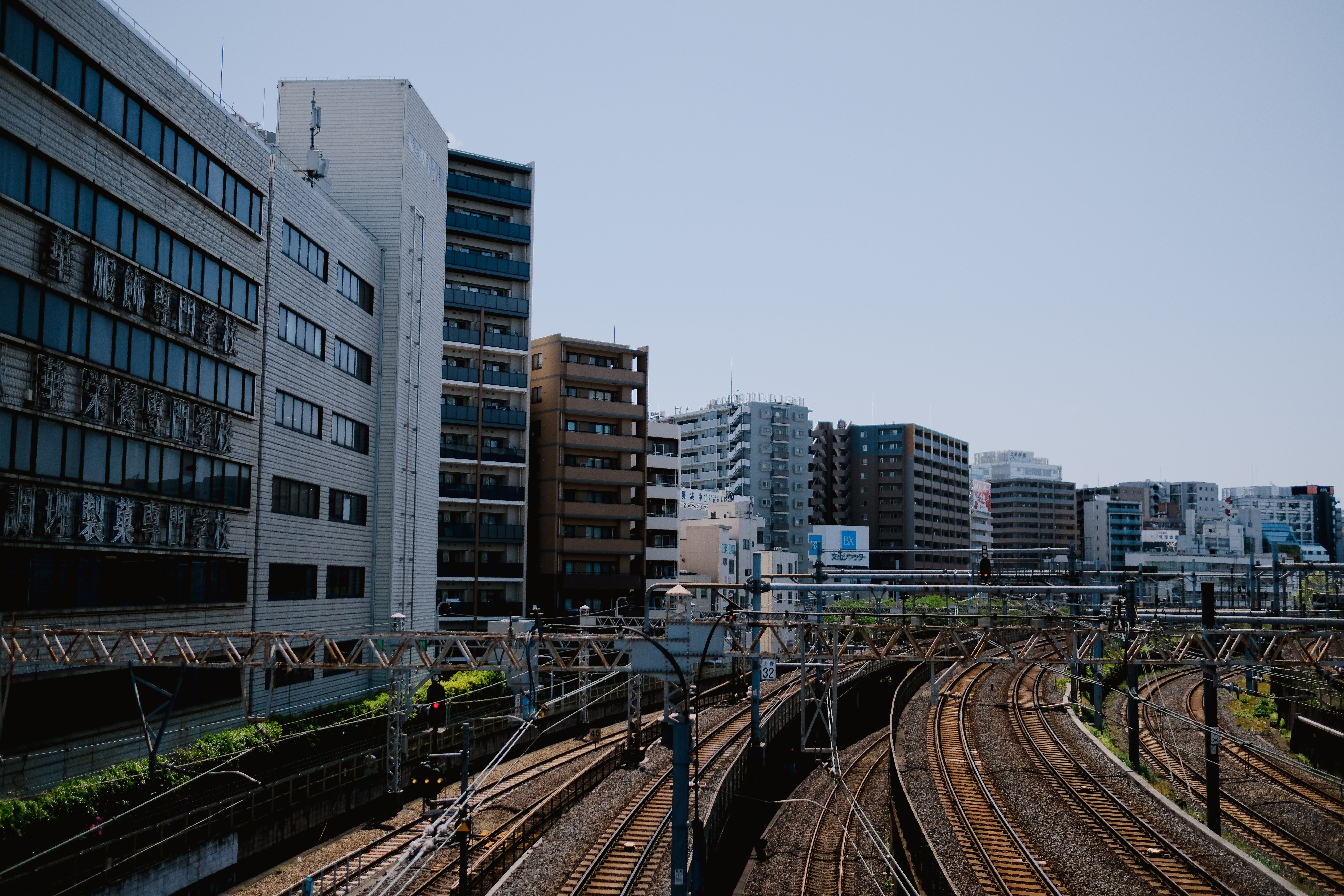 Sunlit urban scene featuring railway tracks flanked by modern buildings.