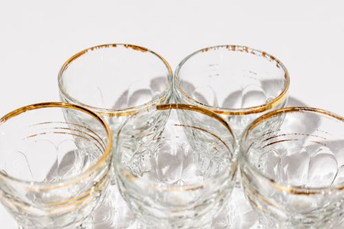 Free Elegant shot glasses with golden rims arranged on a white surface. Stock Photo