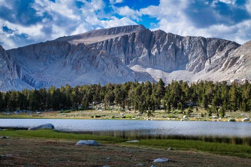 Free Stunning view of a towering mountain behind a lush forest by a tranquil lake. Stock Photo