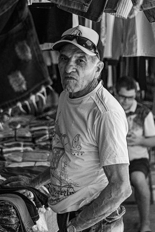 A Man at the Bazaar next to a Stall with Clothing 