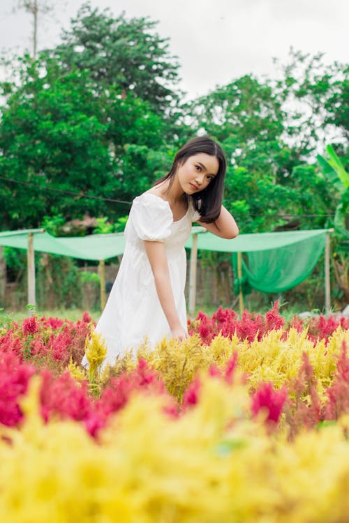Woman in White Dress Posing among Colorful Flowers