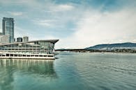 在晴朗的蓝天下，可以欣赏到现代海滨建筑、山脉和城市建筑的壮丽景色