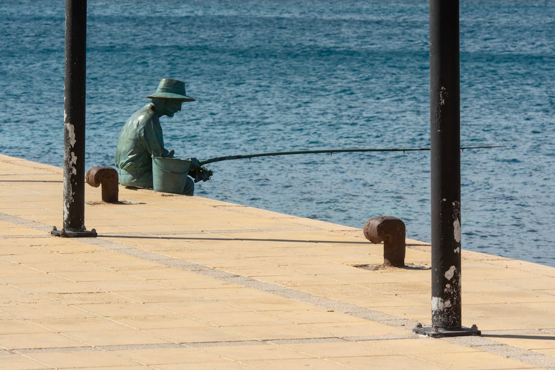 A statue of a man fishing on the pier · Free Stock Photo