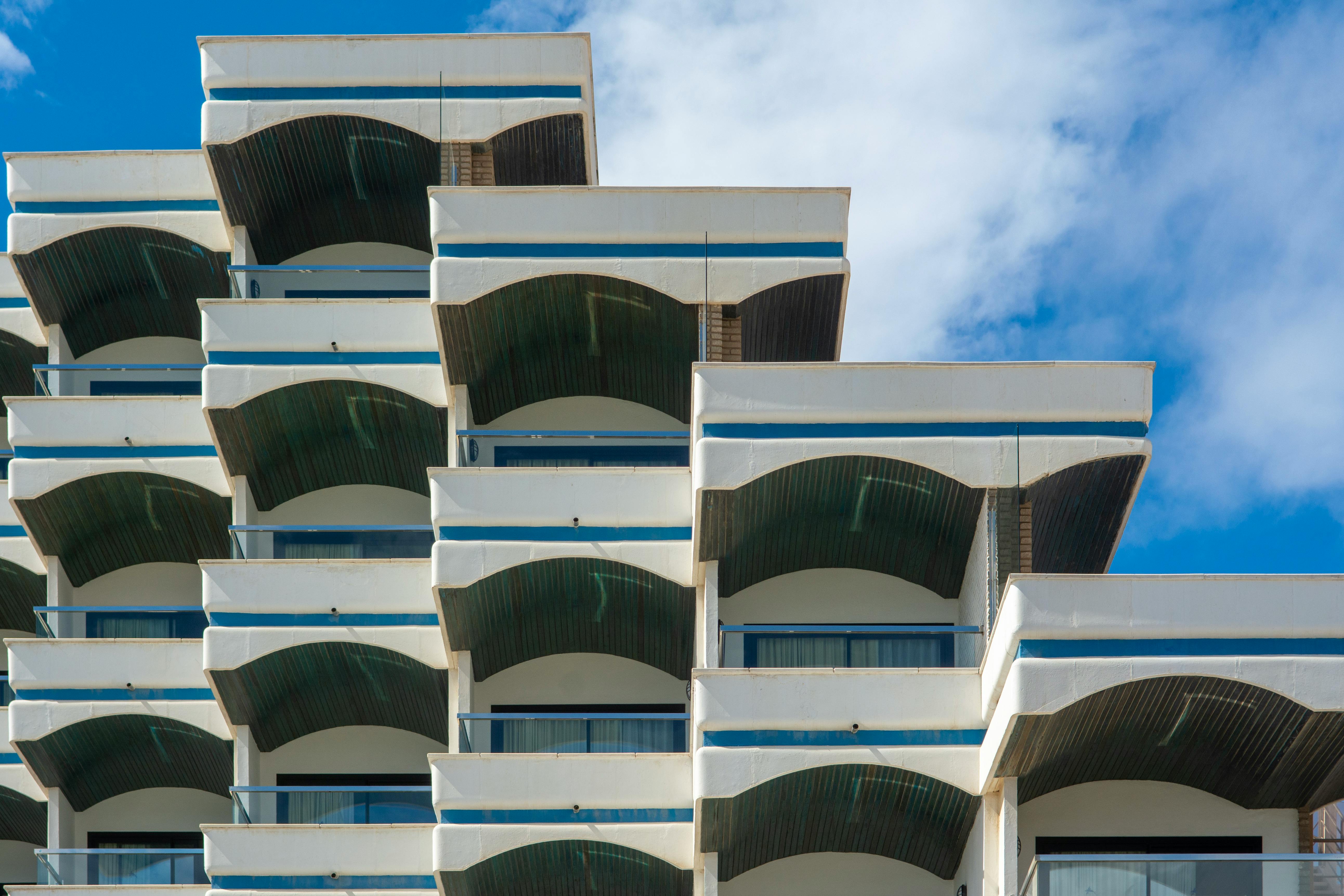 Close-up of modern geometric architecture featuring multiple balconies with blue skies.