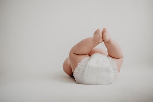 Free Cute baby lying on back in a diaper against a soft, white background. Stock Photo