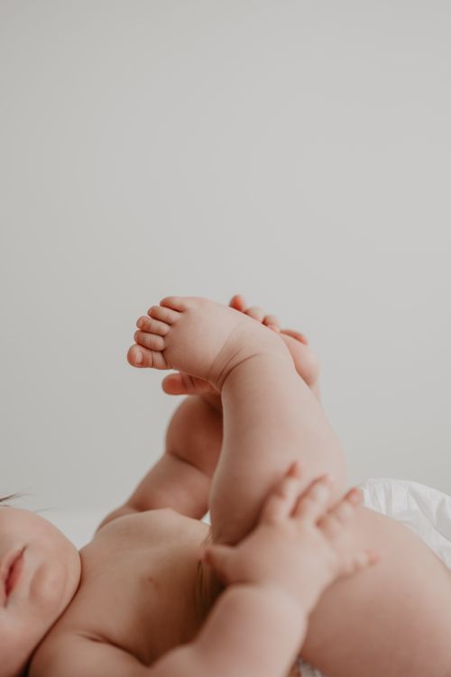 Free Heartwarming close-up of a baby lying down, focusing on tiny hands and feet. Stock Photo
