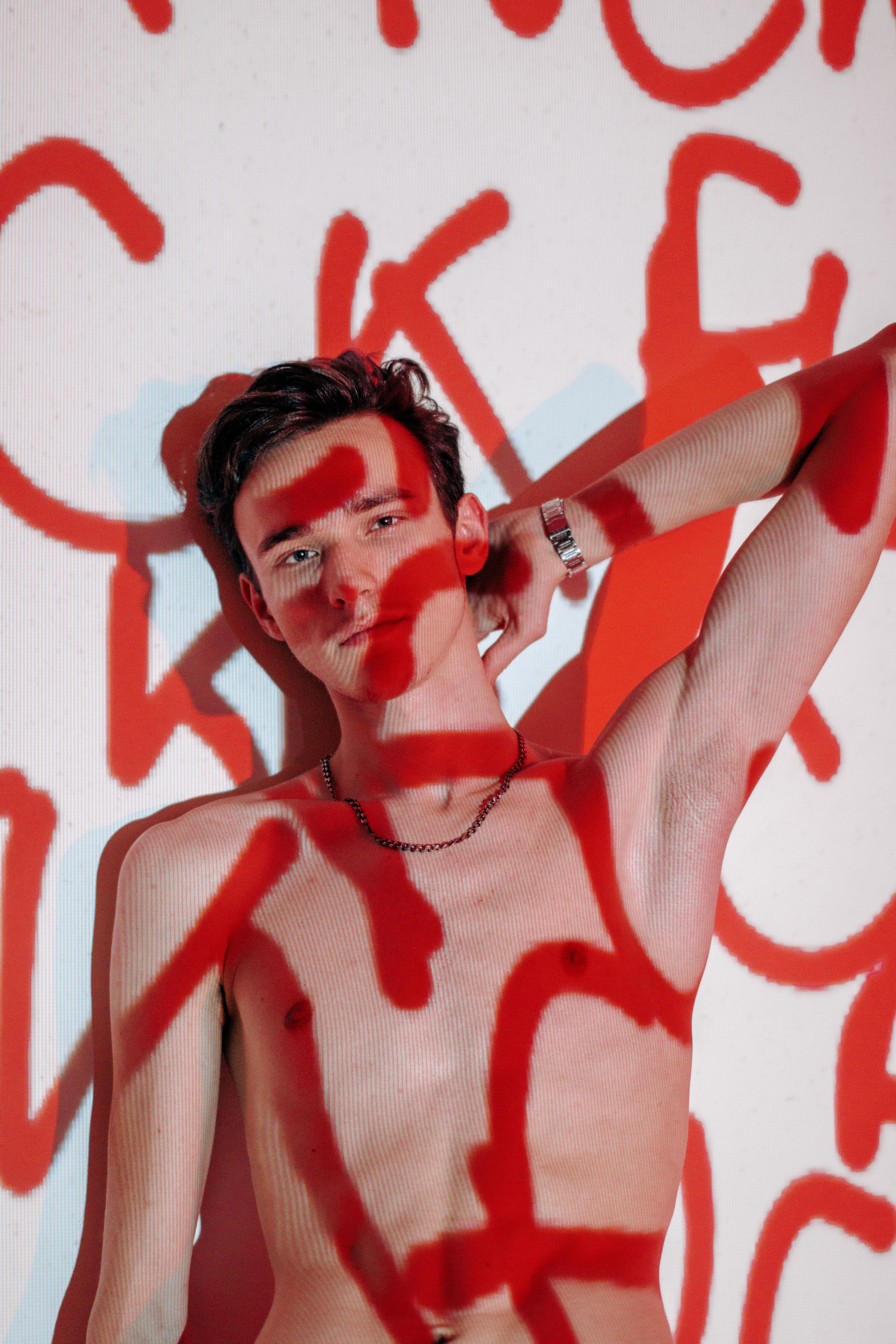 An artistic portrait of a young man with red light patterns. Stylish and bold fashion photography.