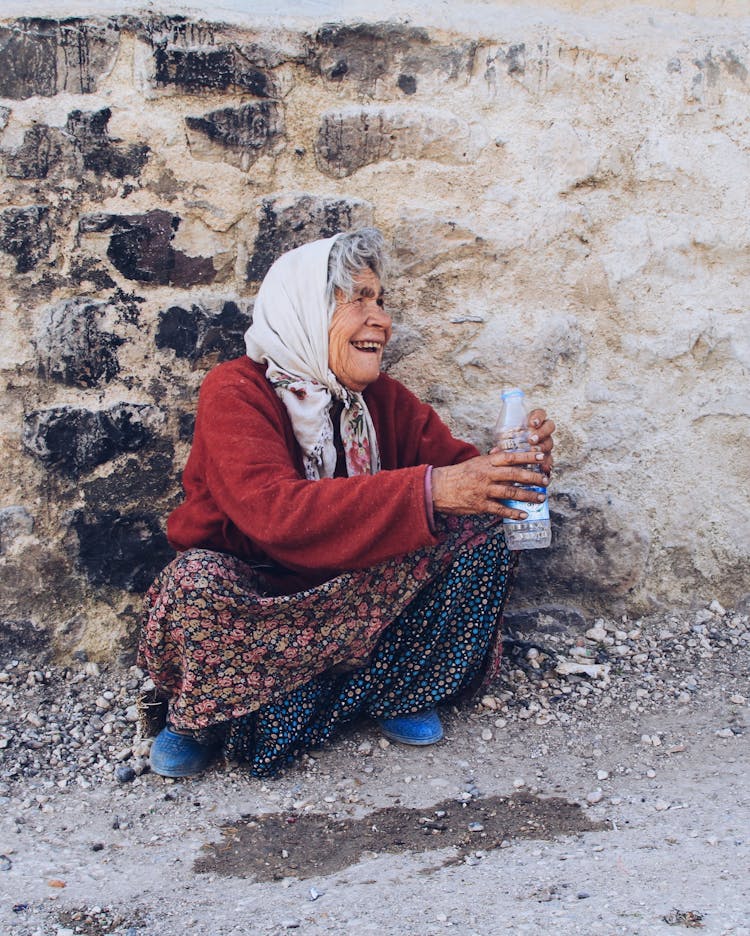 Photo Of A Senior Woman Crouching By A Wall And Smiling