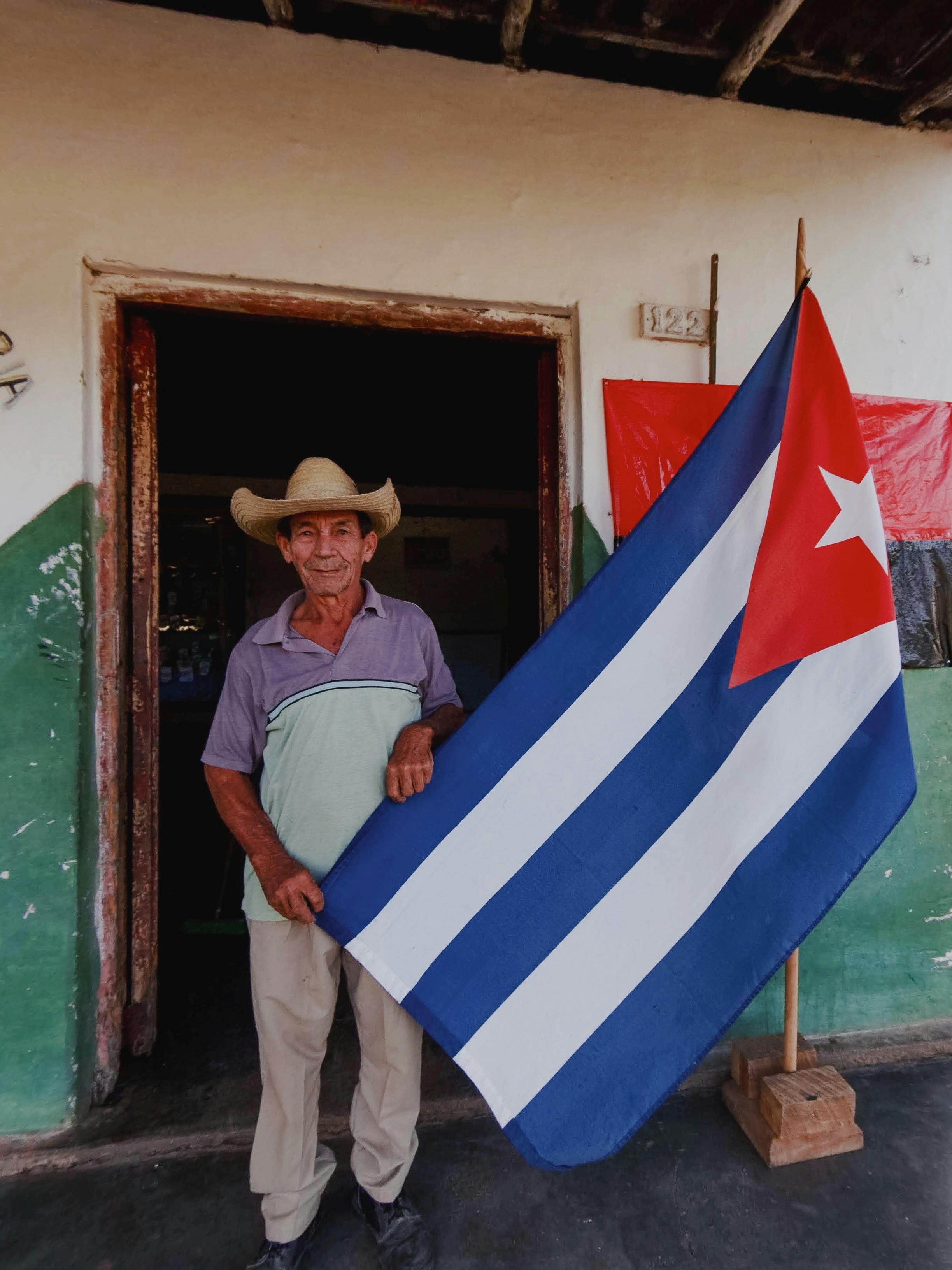 old man in cowboy hat posing near flag