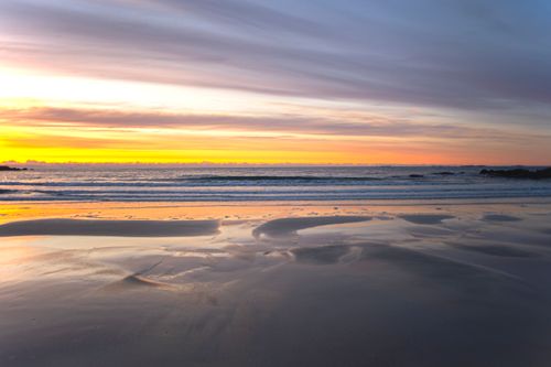 Free Serene sunset view on a tranquil coastal beach with glowing colors and calm ocean waves. Stock Photo