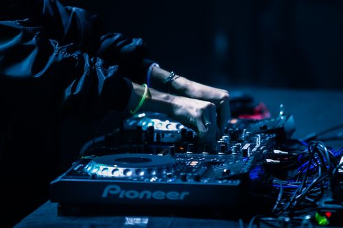 Free Close-up of DJ hands mixing music on a Pioneer controller at a vibrant nightclub. Stock Photo