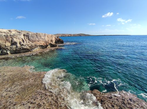 Free A stunning coastal scene with clear blue water, rocky cliffs, and a serene horizon. Stock Photo